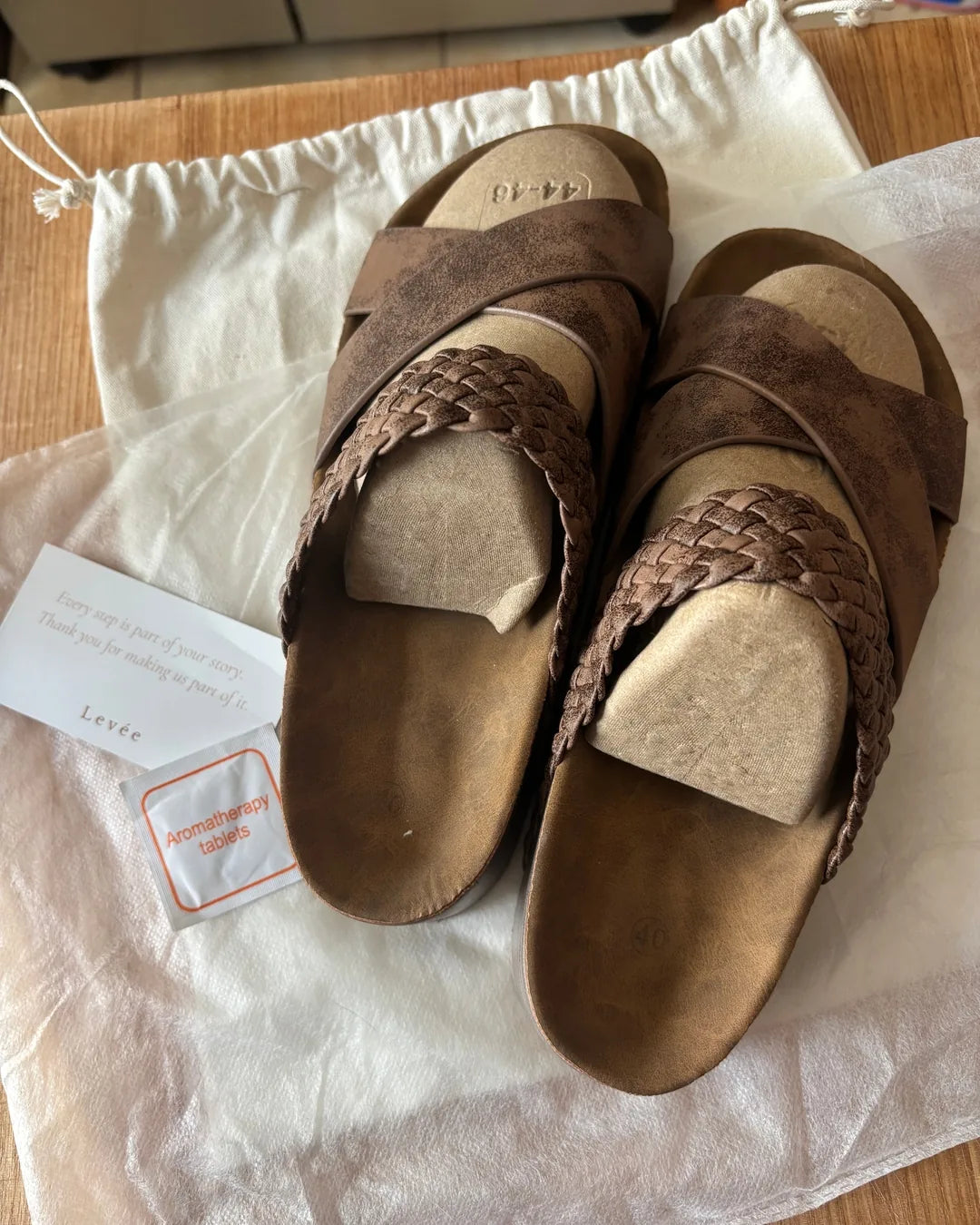 A customer's new pair of Signature Sandals in Dune, just out of the box on the Levée dust bag.